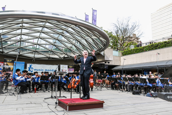 Maestro Bramwell Tovey conducts the mass ensemble in a performance of “We Are One” photo credit William Luk